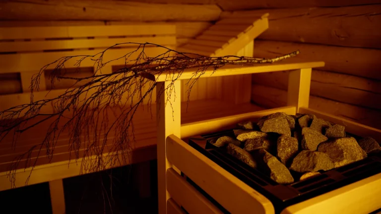 Wooden sauna interior with birch whisk resting on bench amid rising steam