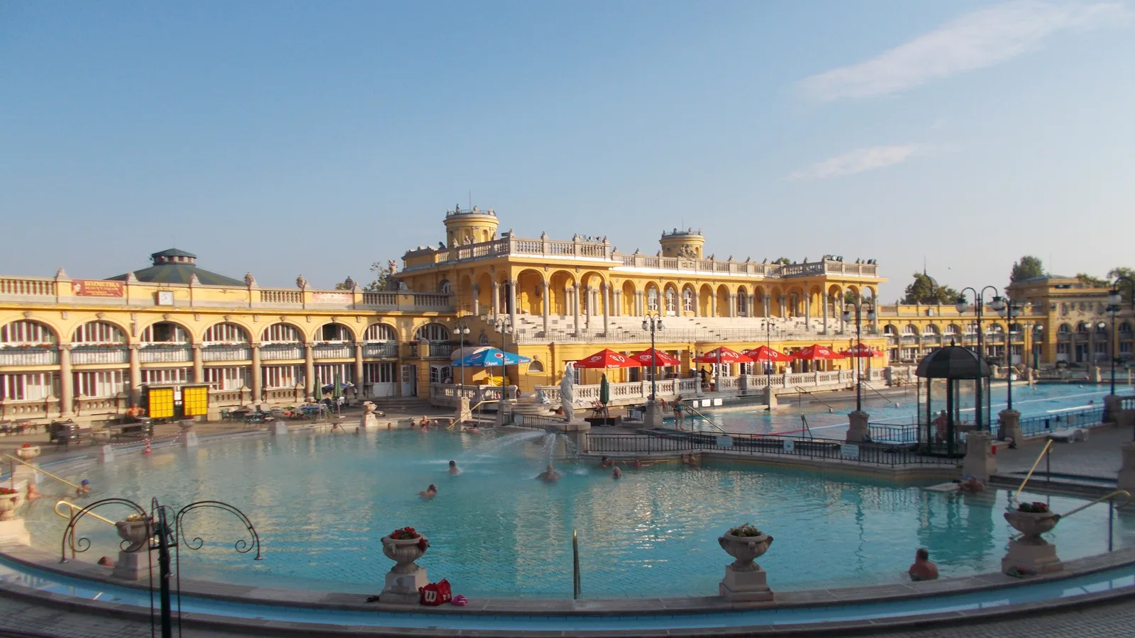 Outdoor pool at Széchenyi Baths in Budapest with the yellow neo-baroque bath building behind it