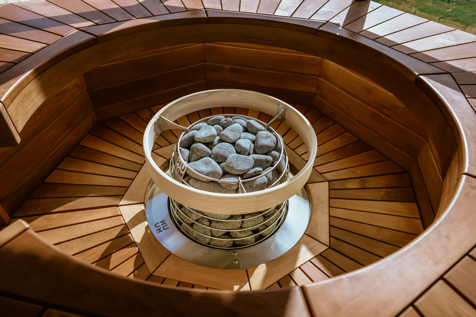 Weathered wooden sauna door with an iron latch, a birch whisk on a nail and a wooden bucket on the step in evening light
