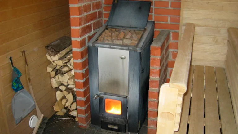 Narvi wood-burning sauna stove with a fire in the firebox, set between brick walls in a Finnish home sauna