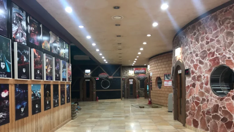 A tiled corridor in a Korean jjimjilbang with a stone kiln sauna and round porthole windows