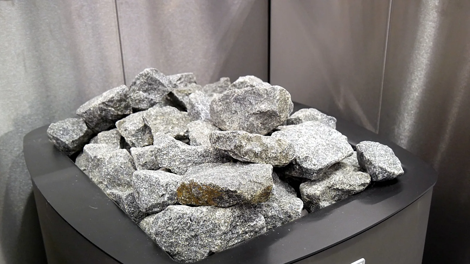 Split grey sauna stones piled on top of an electric sauna heater